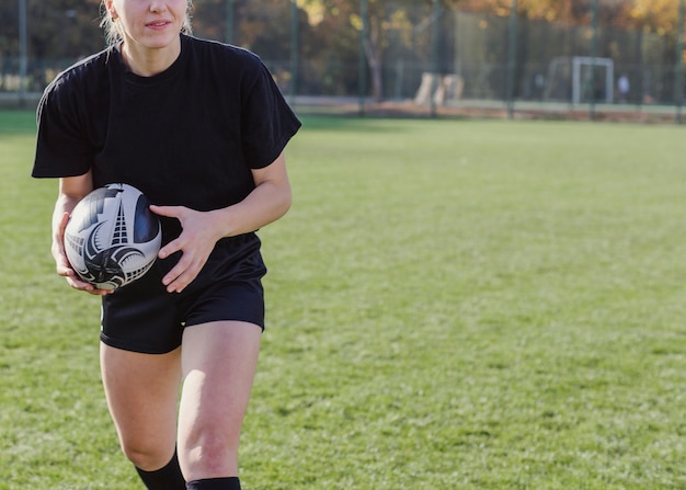 Mani atletiche della donna che tengono una palla di rugby