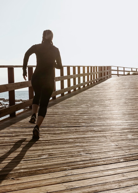 Free photo athletic woman jogging by the beach with copy space