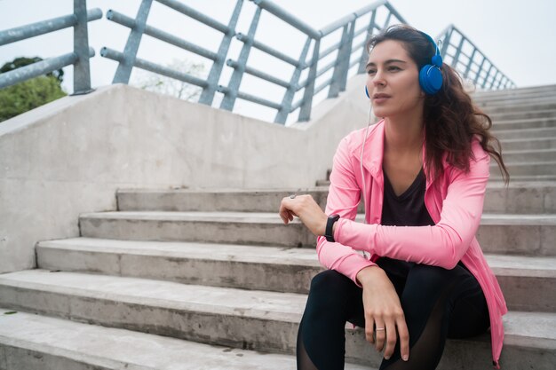 Athletic woman listening to music on a break from training