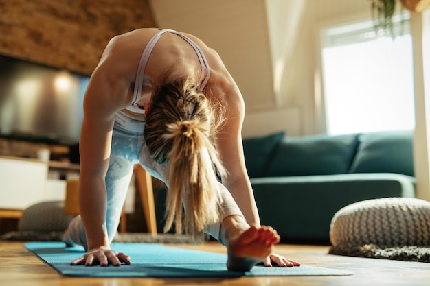 Athletic woman stretching on the floor while practicing at home.