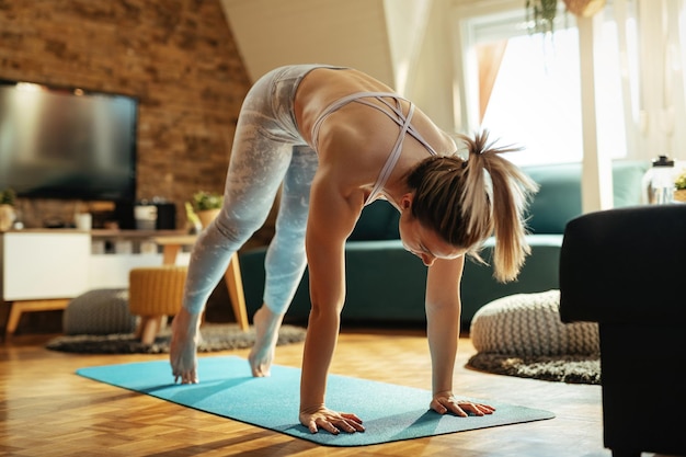 Athletic woman warming up and stretching while exercising at home.