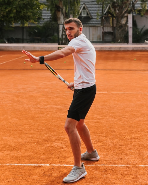 Атлетик мальчик играет в теннис