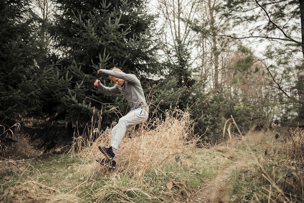 Атлетик молодой мужчина прыгает над травой, пока спортивная подготовка