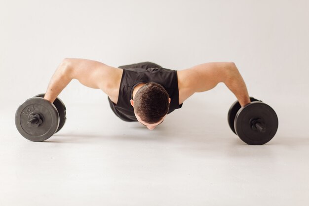 Athletic young man doing workouts at home, man doing training, warm up before weight exercise.