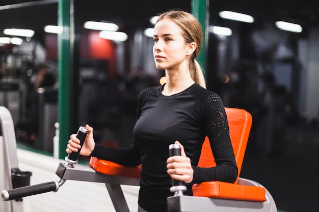Атлетик молодая женщина делает упражнения в фитнес-центре