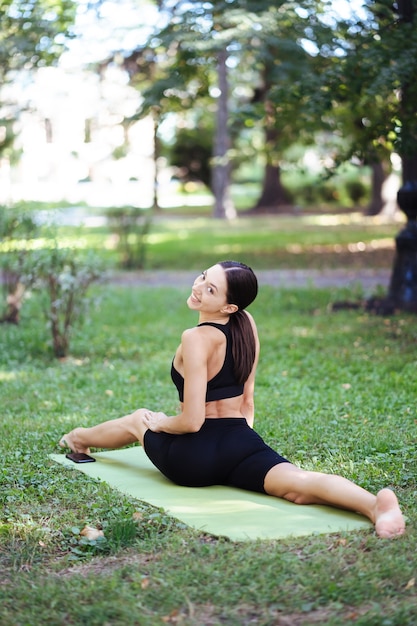 午前中に公園でヨガをしている運動の若い女性、ヨガマットの女性のトレーニング