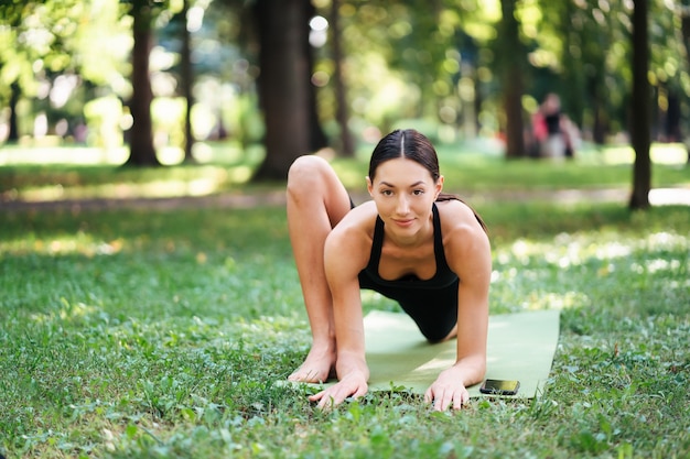 午前中に公園でヨガをしている運動の若い女性、ヨガマットの女性のトレーニング