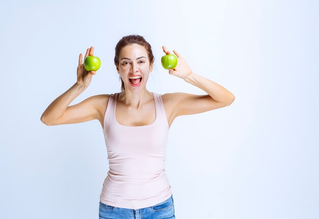 Спортивная (ый) молодая женщина, держащая зеленые яблоки