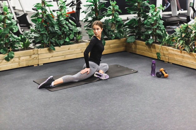 Athletic young woman stretching her leg in gym