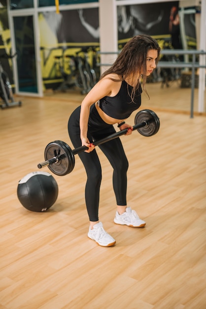 Free photo athletic young woman training with barbells in gym
