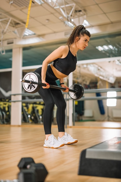 Athletic young woman training with barbells