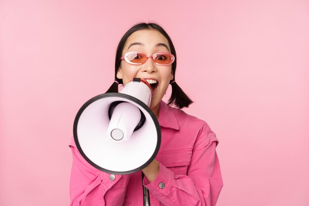 주의 발표 개념 분홍색 배경 위에 서 있는 연사 모집과 함께 확성기 광고에서 외치는 열정적인 아시아 소녀