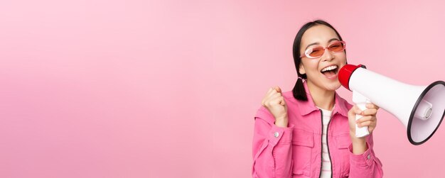 주의 발표 개념 분홍색 배경 위에 서 있는 연사 모집과 함께 확성기 광고에서 외치는 열정적인 아시아 소녀