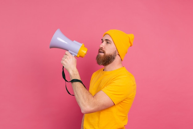 Foto gratuita attenzione! uomo europeo che grida nel megafono su sfondo rosa