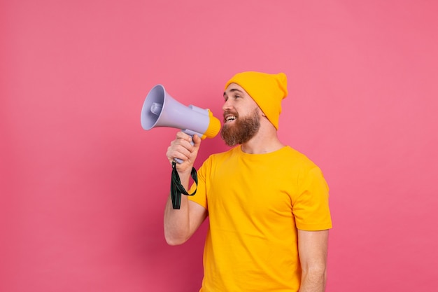 Attention! European man shouting in megaphone on pink background