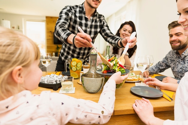 Attentive man putting salad for child