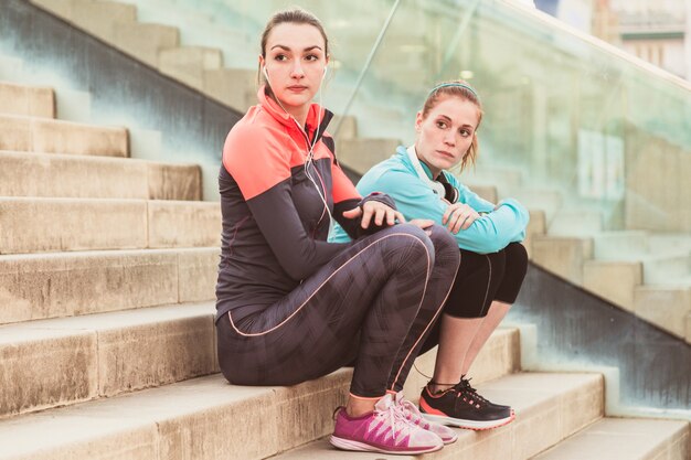 attentive sportswomen sitting on stairs