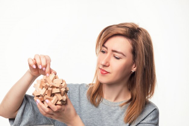 Attractive 24 year old business woman looking confused with wooden puzzle.