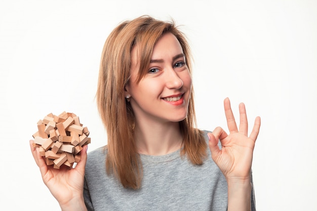 Attractive 24 year old business woman looking confused with wooden puzzle.