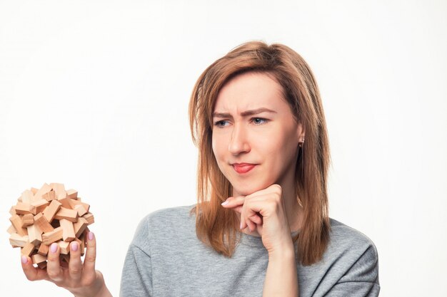 Attractive 24 year old business woman looking confused with wooden puzzle.