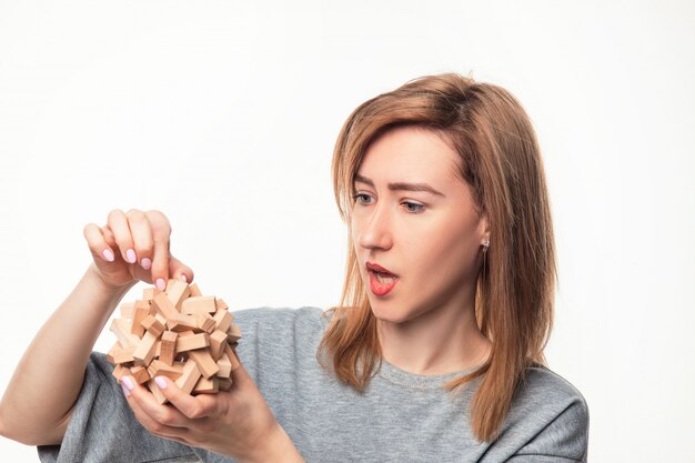 Attractive 24 year old business woman looking confused with wooden puzzle.