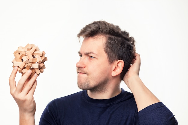 Free photo attractive 25 year old business man looking confused at wooden puzzle.