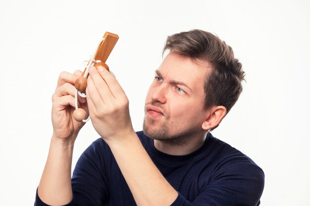 Attractive 25 year old business man looking confused at wooden puzzle.
