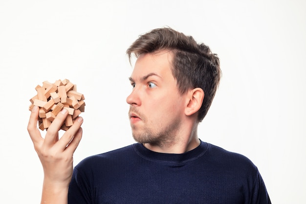 Attractive 25 year old business man looking confused at wooden puzzle.