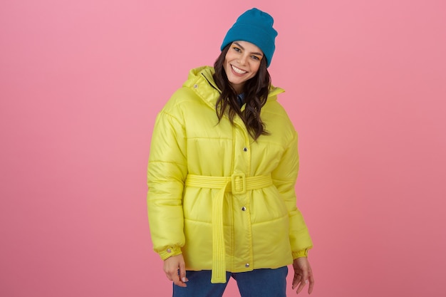 Foto gratuita attraente donna attiva in posa sul muro rosa in piumino invernale colorato di colore giallo brillante, divertimento sorridente, tendenza moda cappotto caldo, espressione faccia sorpresa scioccata pazza