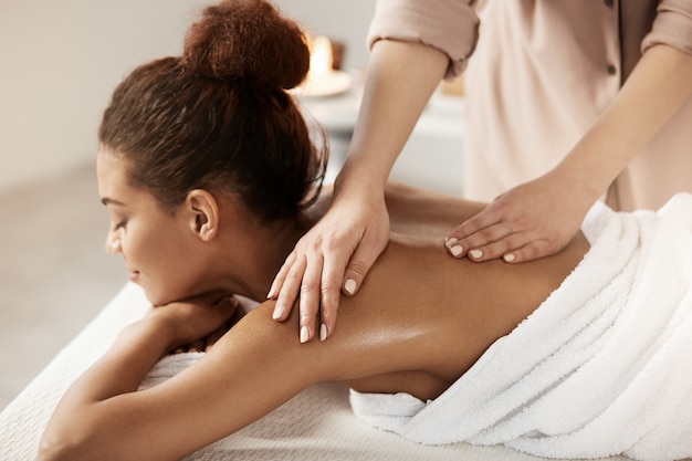 Free photo attractive african woman having massage relaxing in spa salon. closed eyes.