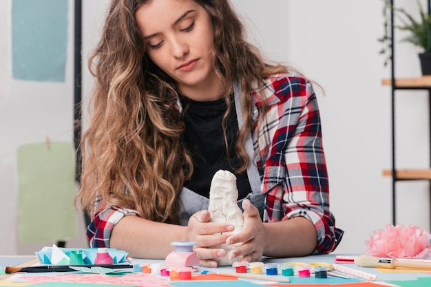 Foto gratuita artista attraente che fa arte di handcraft usando argilla bianca
