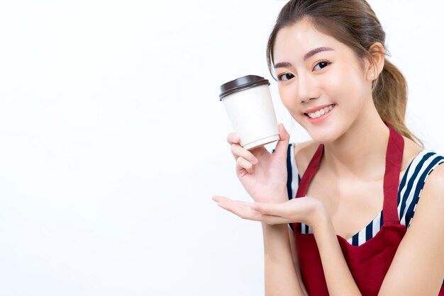 Привлекательная азиатская женщина-владелец бизнеса с рукой в фартуке представляет тройку кофе, горячий напиток, счастье и радостную концепцию владельца бизнеса