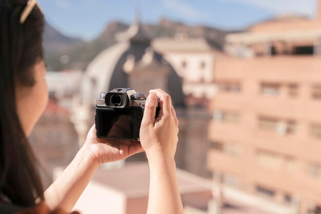 魅力的なアジアの女性旅行者の観光の手は、幸福と陽気な旅行の旅のコンセプトを持つカルタヘナスペインのカメラ観光古い家の建物のアーキテクチャを使用します