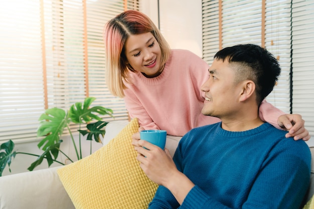 Attractive Asian sweet couple enjoy love moment drinking warm cup of coffee or tea in their hands 