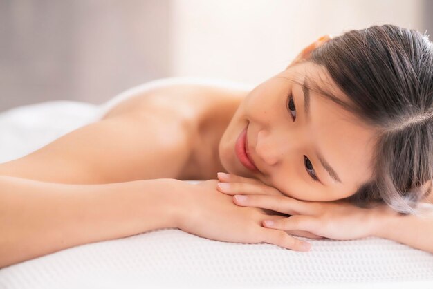 Привлекательная азиатская женщина наслаждается восточным массажем и моллюсками, белая кровать, идеи здорового образа жизни