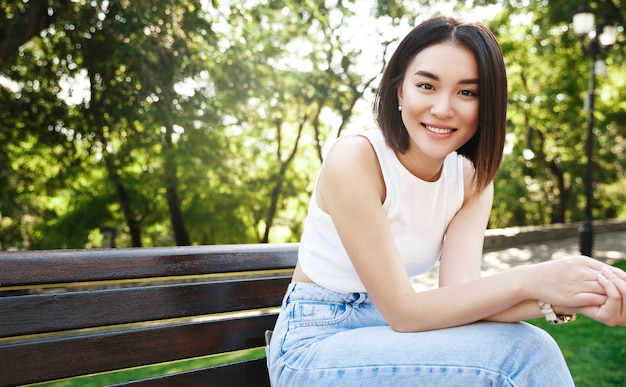 Привлекательная азиатская женщина, расслабляющаяся в парке