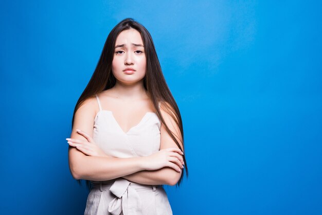 Attractive asian woman standing isolated on blue wall