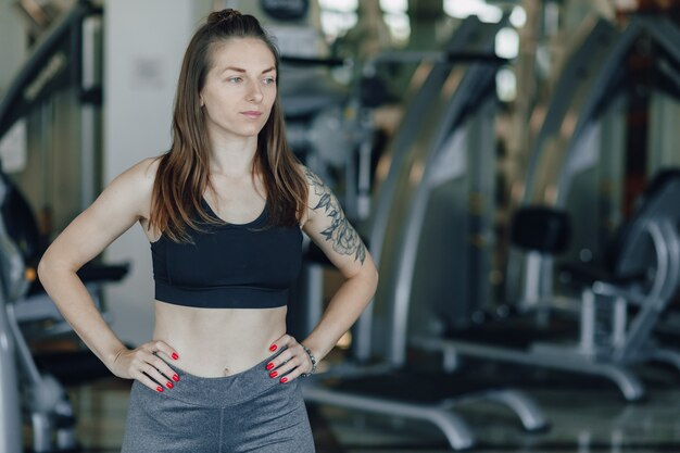 Attractive athletic girl stands on the background of simulators in the gym. healthy lifestyle.