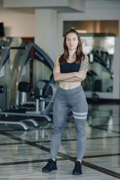 매력적인 운동 소녀 체육관에서 시뮬레이터의 배경에 서있다. 건강한 생활.
