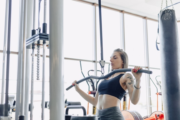 Attractive athletic girl trains shoulders in simulator. view of the back muscles. healthy lifestyle.