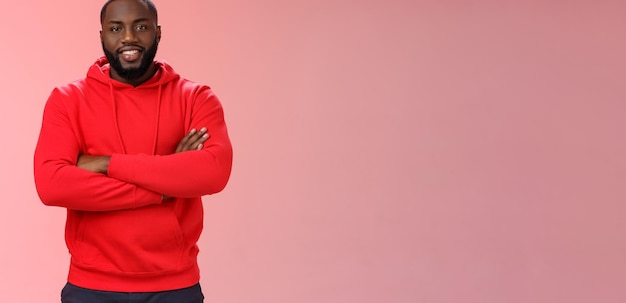 Attractive bearded africanamerican young guy wearing red hoodie cross arms chest smiling friendly