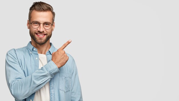 Attractive bearded guy posing against the white wall