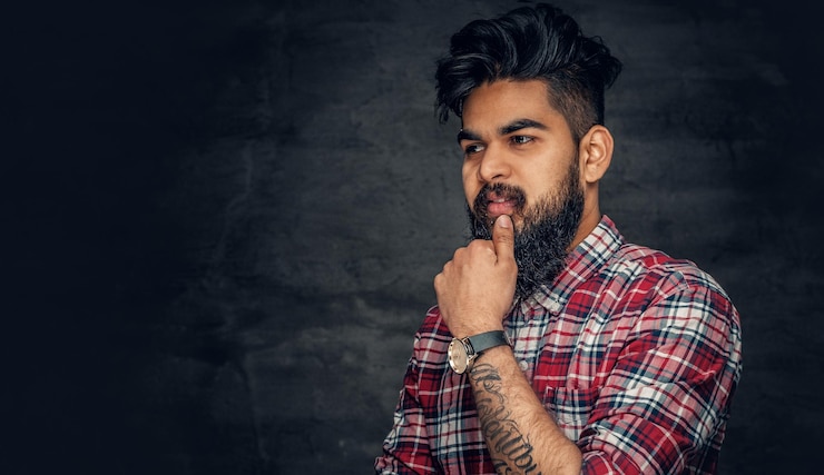 मुफ़्त फोटो attractive bearded indian man in plaid fleece shirt over grey background.