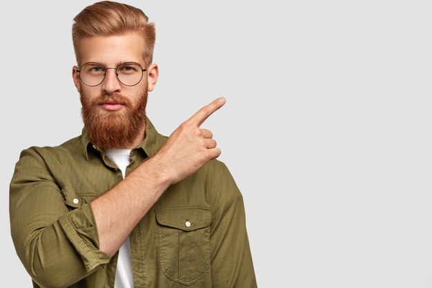 attractive bearded male with thick ginger beard and hair, appealing look, points at upper right corner
