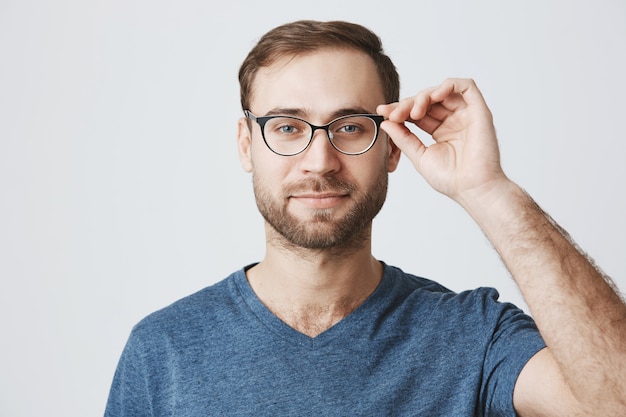 Attractive bearded man picking glasses at optician store