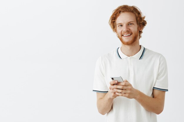 Attractive bearded redhead guy posing against the white wall