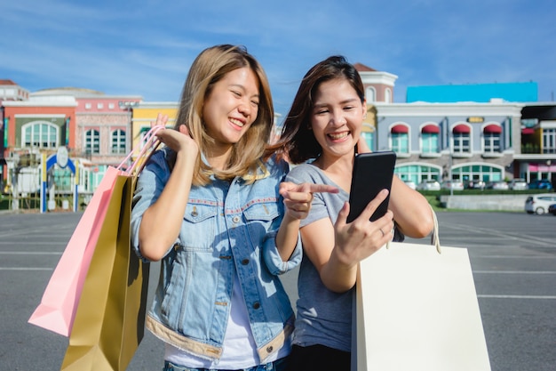 Attractive beautiful asian woman using a smartphone while shopping in the city