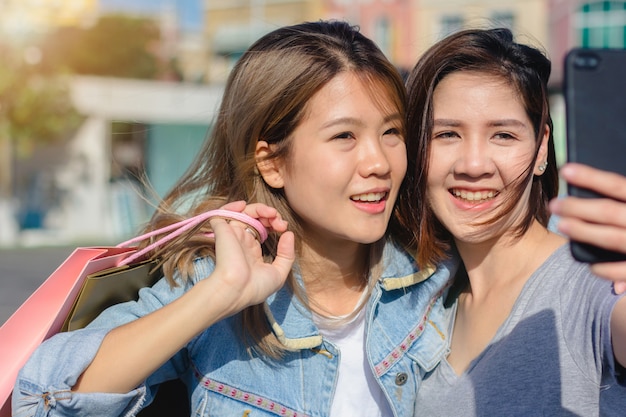 Attractive beautiful asian woman using a smartphone while shopping in the city