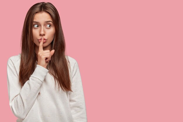 Attractive beautiful brunette posing against the pink wall