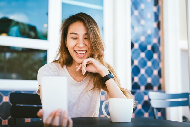 魅力的で美しい、幸せ、若い、アジア人、女、スマートフォン、セルフ、使うこと、カフェ